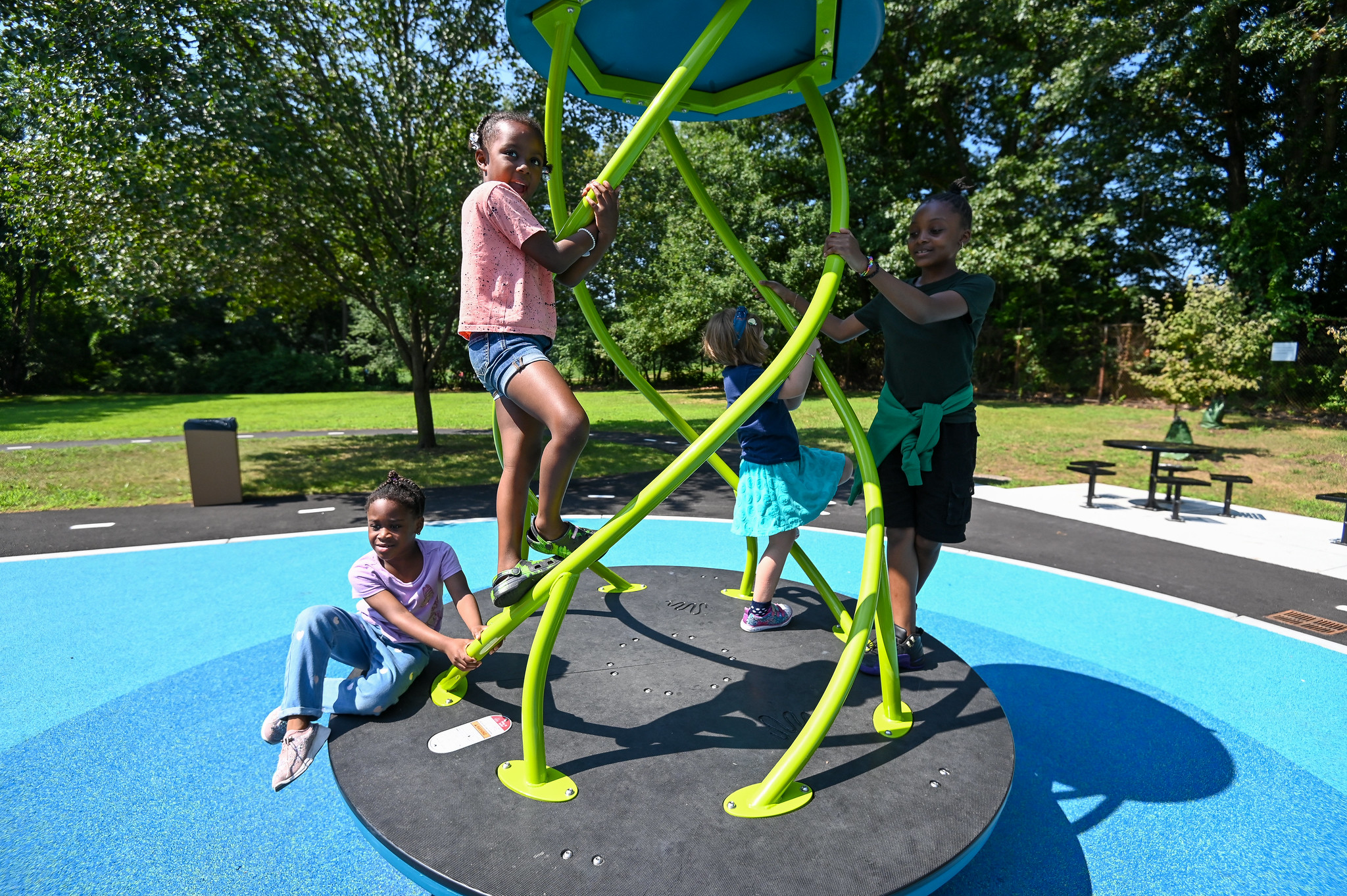 Four children are playing on playground equipment in the sun