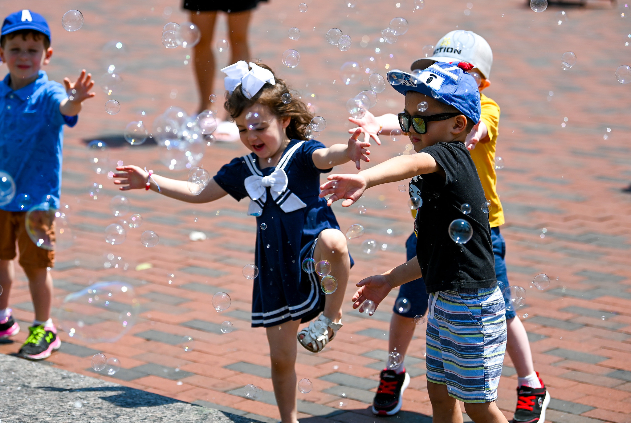 four young children play with bubbles
