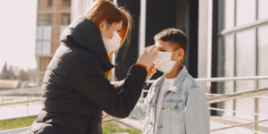 An adult putting a face covering on a child