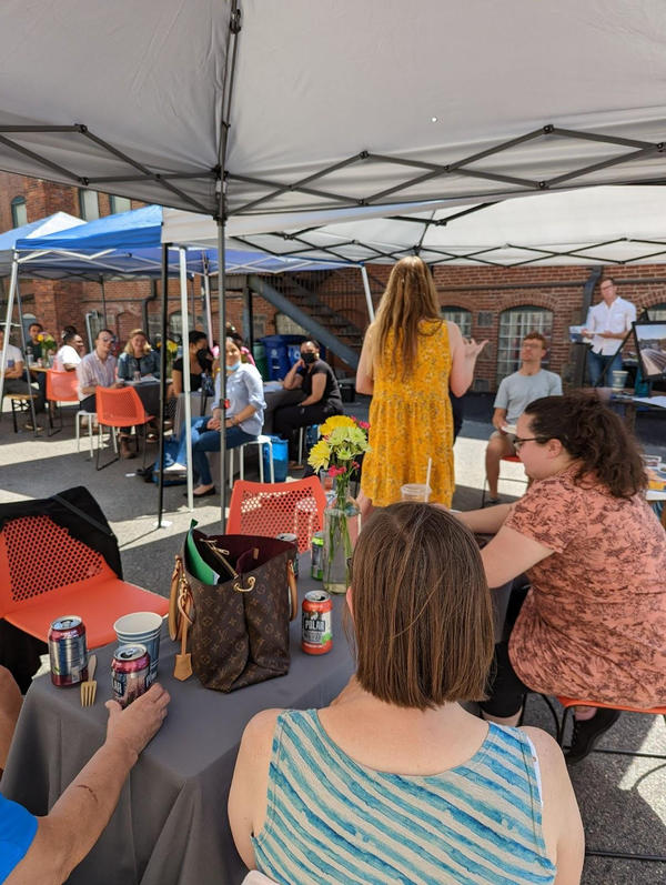 People sit under tents listening to a speaker at the Mujeres Unidos Avanzado event.