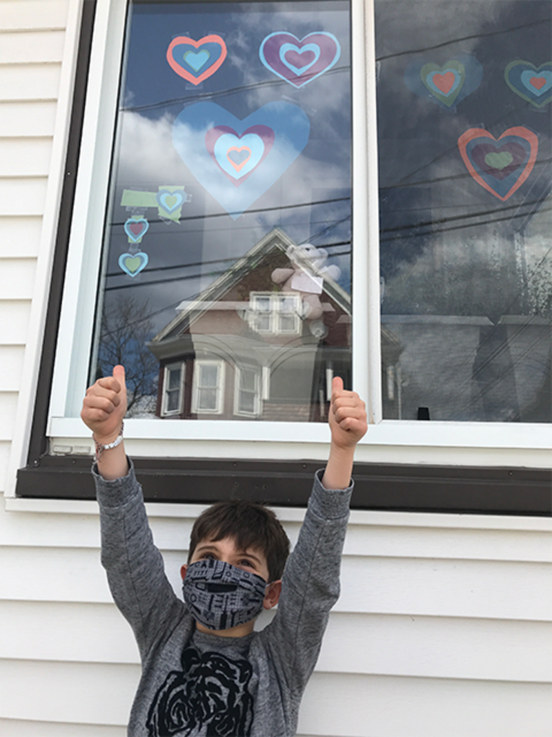photo of boy wearing mask with hearts in window 