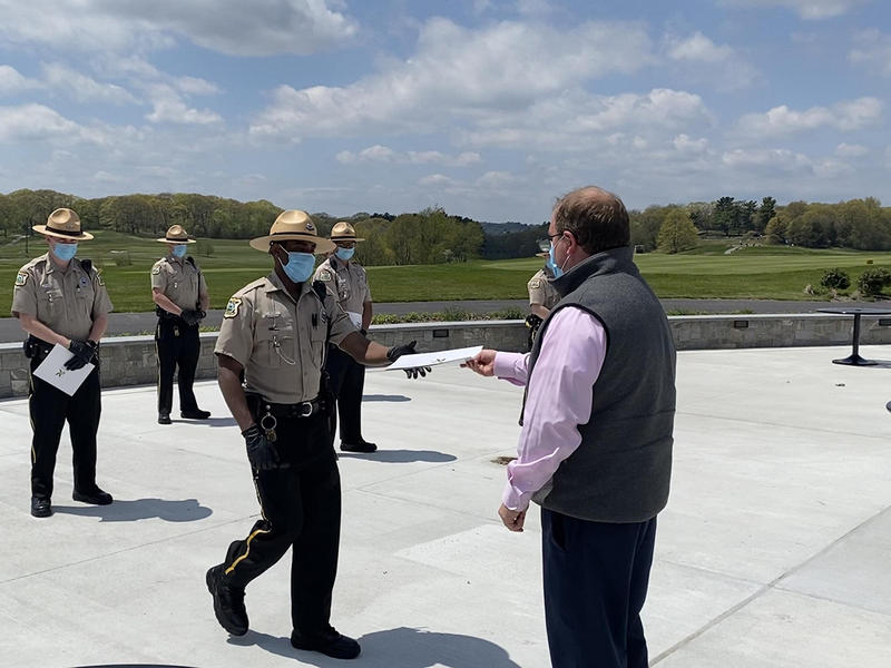 Keeping a safe distance, Commissioner Woods reaches out to hand a new Ranger his certificate.