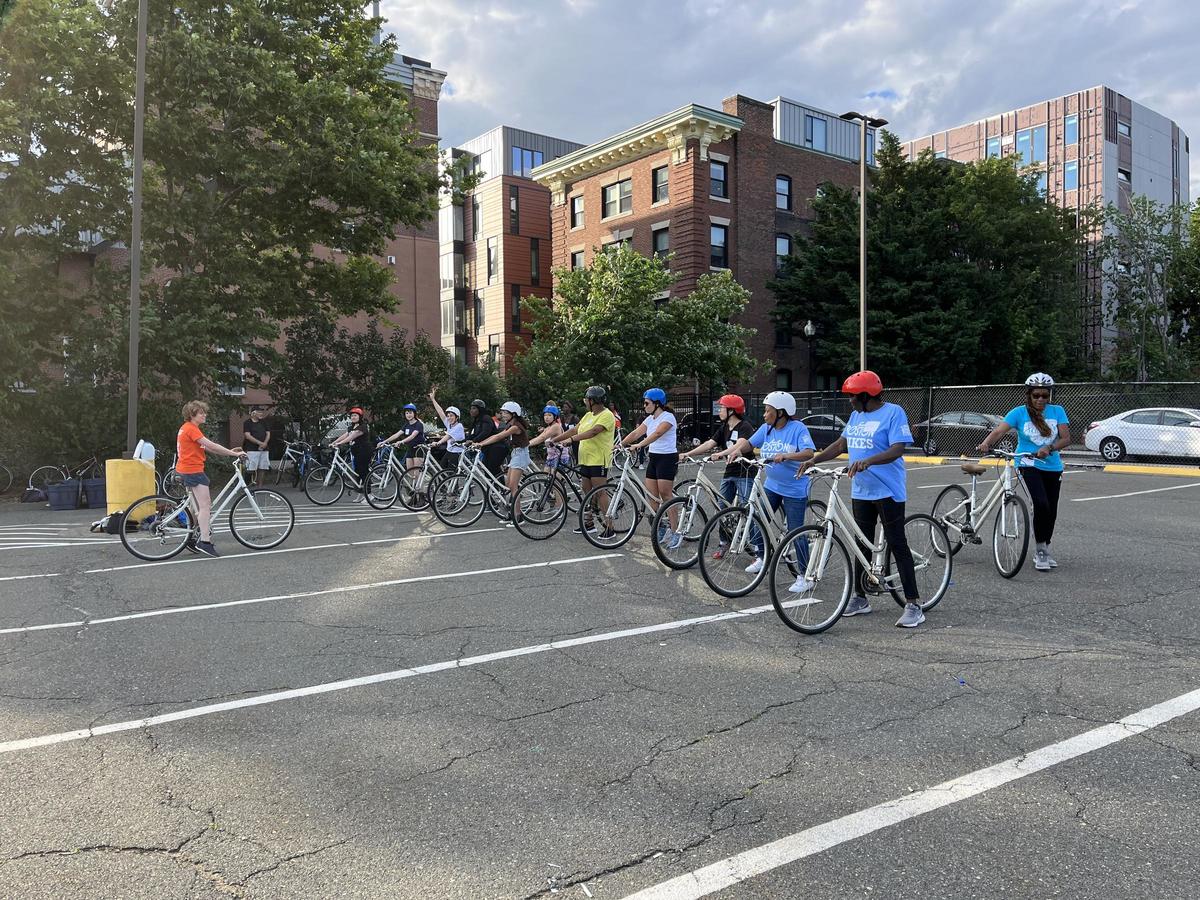 a photo of a group of adult women learning to ride a bike