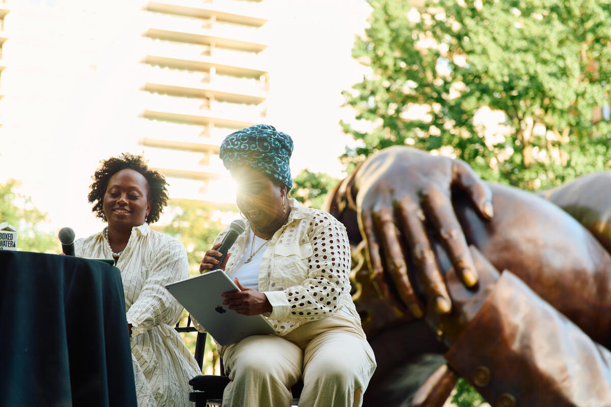 Prof. Kerri Greenidge and Dr. Kyera Singleton on stage in front of The Embrace