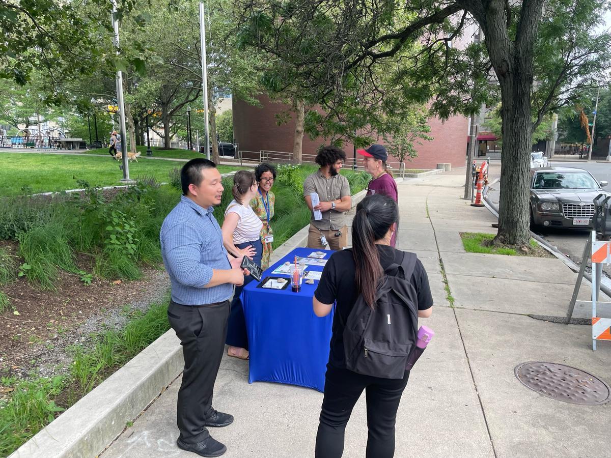 A photo of BTD staff and interpreter standing at a table interacting with constituents