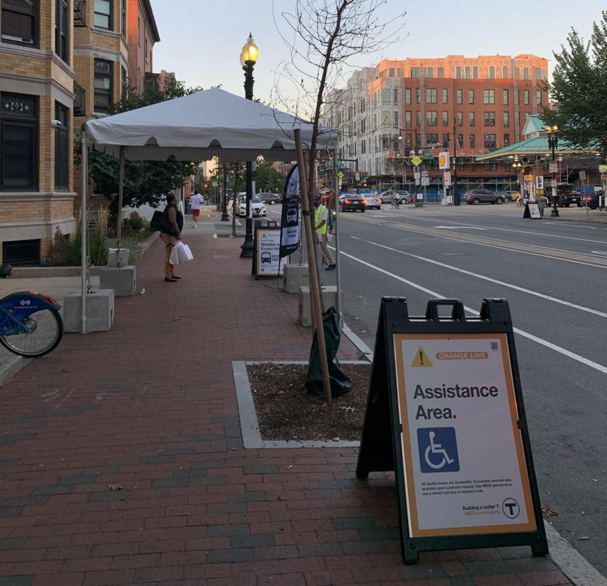 MBTA Closure Shuttle Stop with White tent and sign reading "orange line accessible area" with international symbol of access.