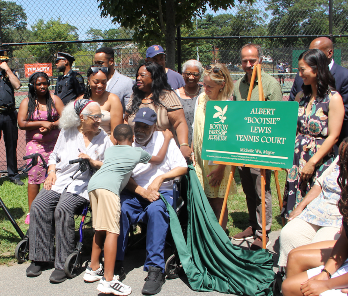 A young child hugs Albert "Bootsie" Lewis as many pose for a picture with Lewis and Mayor Wu