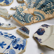 photo of fragments of white-colored ceramics with blue and black painted decoration that look like a shield and knights helmet