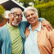 Senior couple smiling in front of house