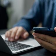 Someone using a cell phone and a laptop