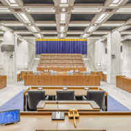 Empty Boston City Council chamber showing desks, chairs, and public seating area