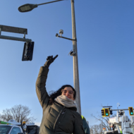 A young lady pointing at the sky during the wintertime.