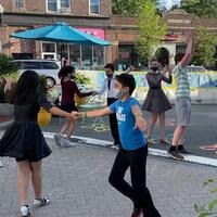 A photo showing kids dancing in a pedestrianized street that has been closed to vehicle traffic