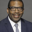 Arthur Jemison wearing a suit, tie, and glasses.