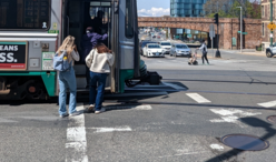 two riders board a green line train at the Riverway Stop